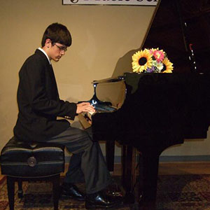 Photo of a student performing on a grand piano in the recital hall.