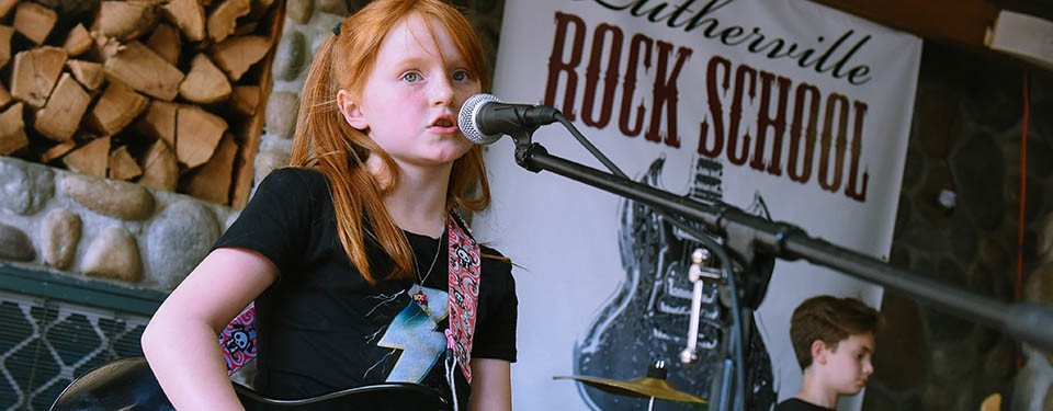 A photo of a student performing at a Lutherville Rock School concert.