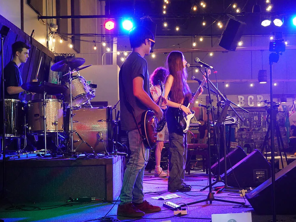 Photo of a student band performing on a variety of instruments on stage.