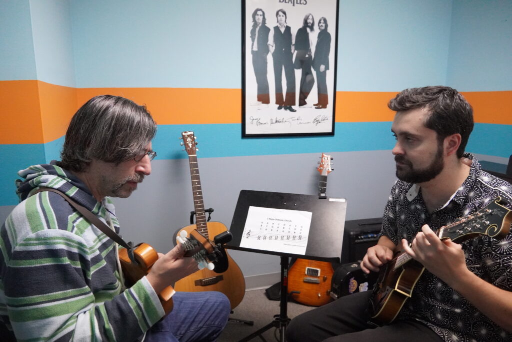 A photo of a student learning mandolin with teacher Connor Murray.