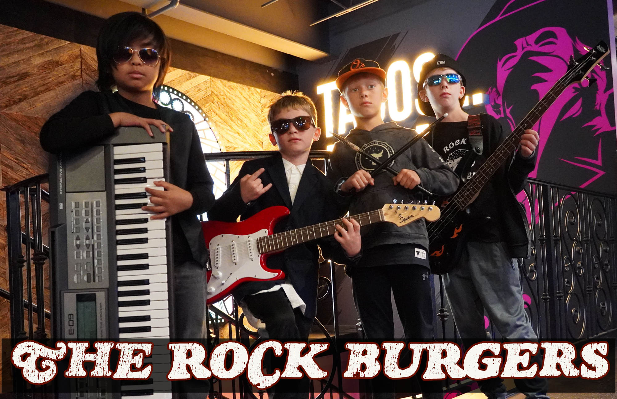 A student band posing with their instruments with the words "The Rock Burgers" along the bottom.