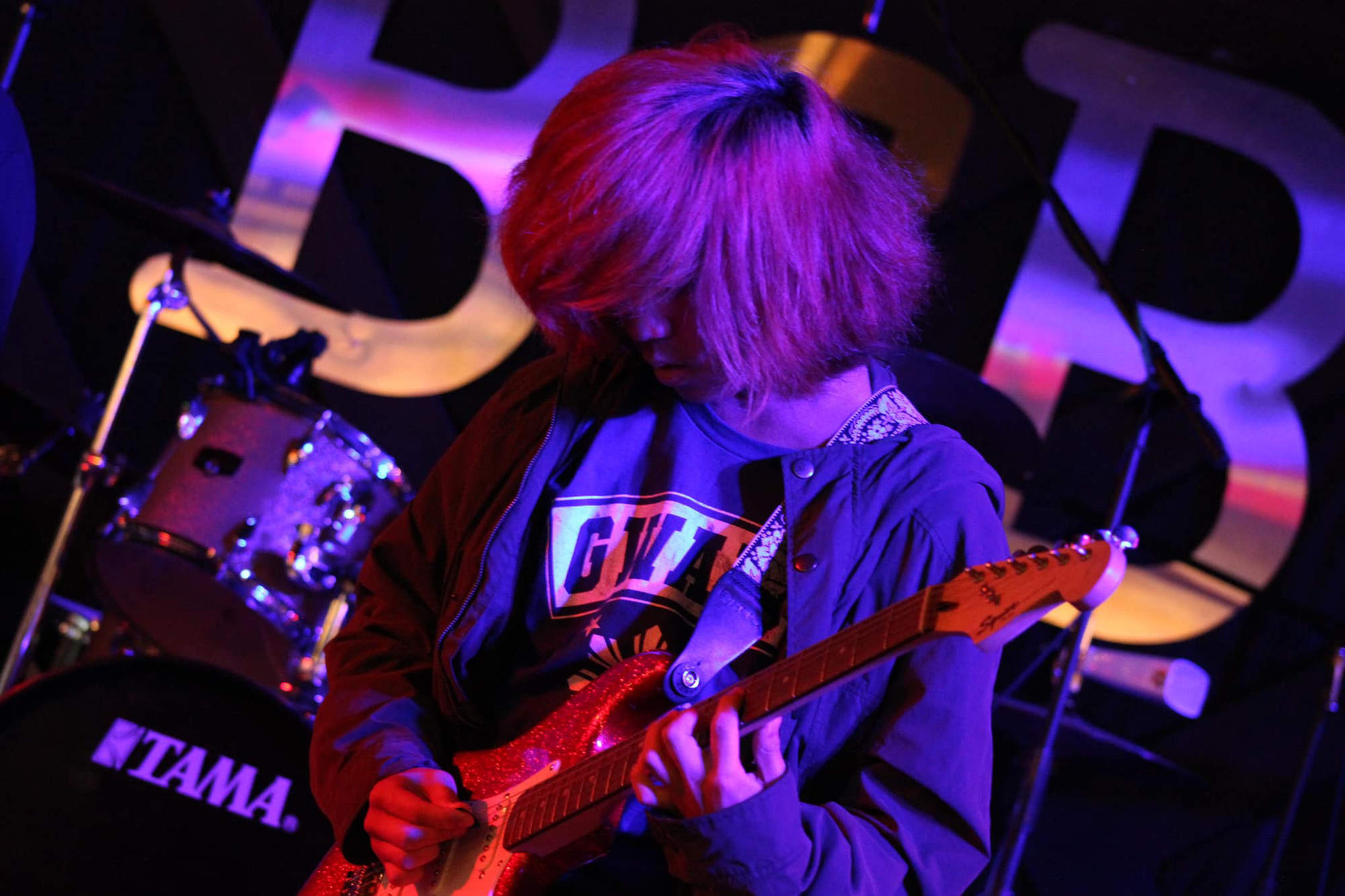 A student playing guitar on stage.