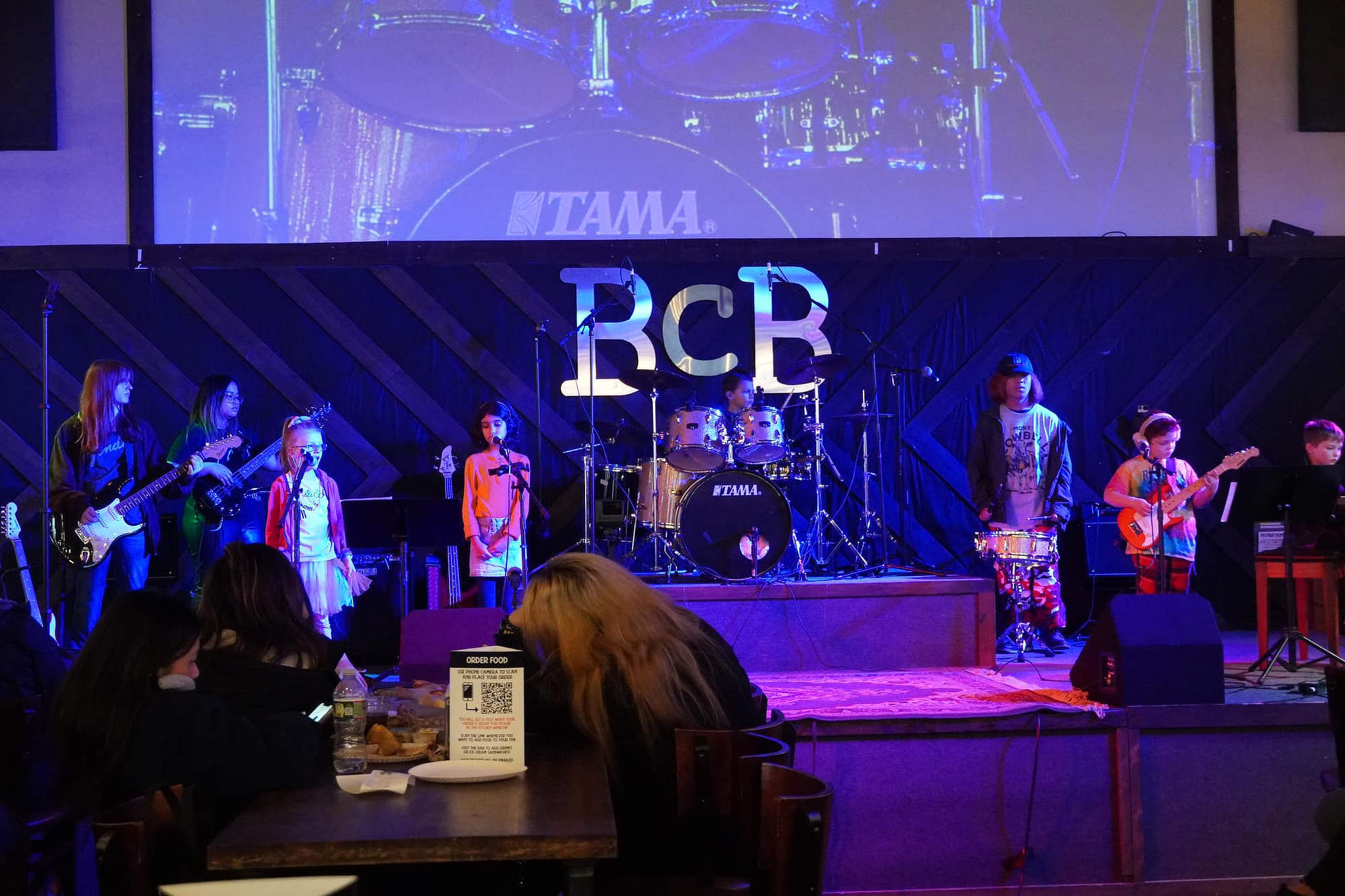 Students performing on stage with the letters BCB seen behind them.