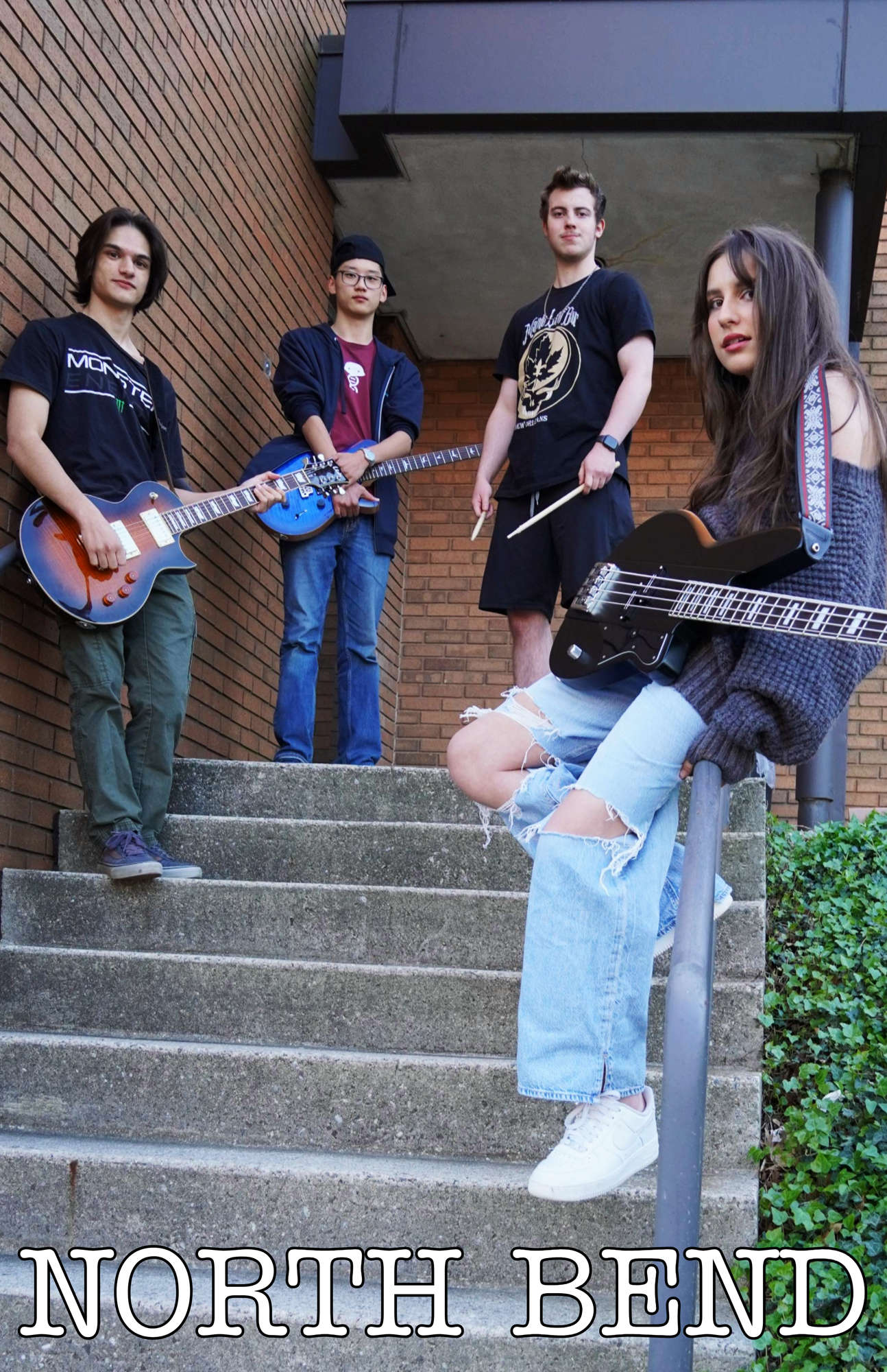 A young group of musicians posing with their instruments on a stair case with the words "North Bend" written below them.