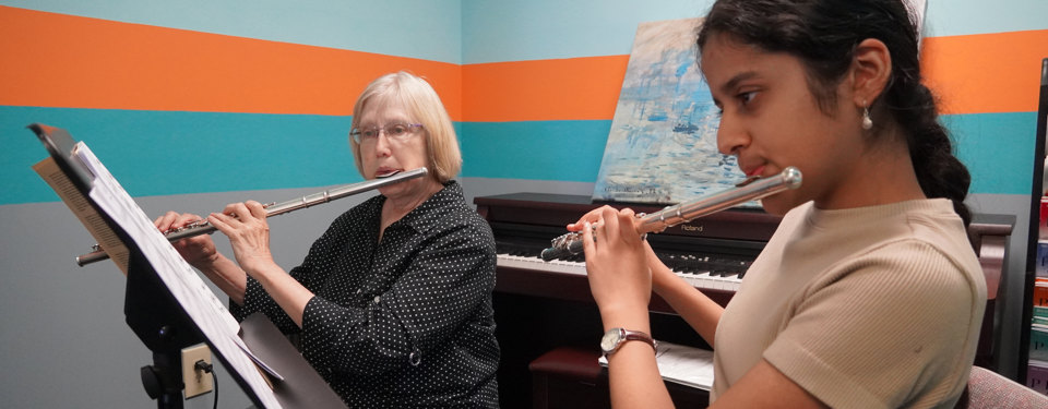 A flute teacher and flute student both performing during a lesson.