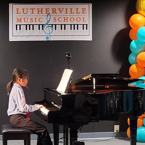 A student performing on a grand piano in the recital hall.