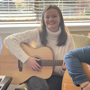 A photo of Suzanne holding an acoustic guitar.