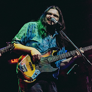 A photo of Chris performing on bass guitar.