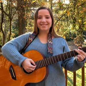 Photo of Emily Sidelnikov holding a guitar.