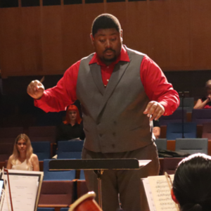 A photo of Darius Sanders conducting a music ensemble.